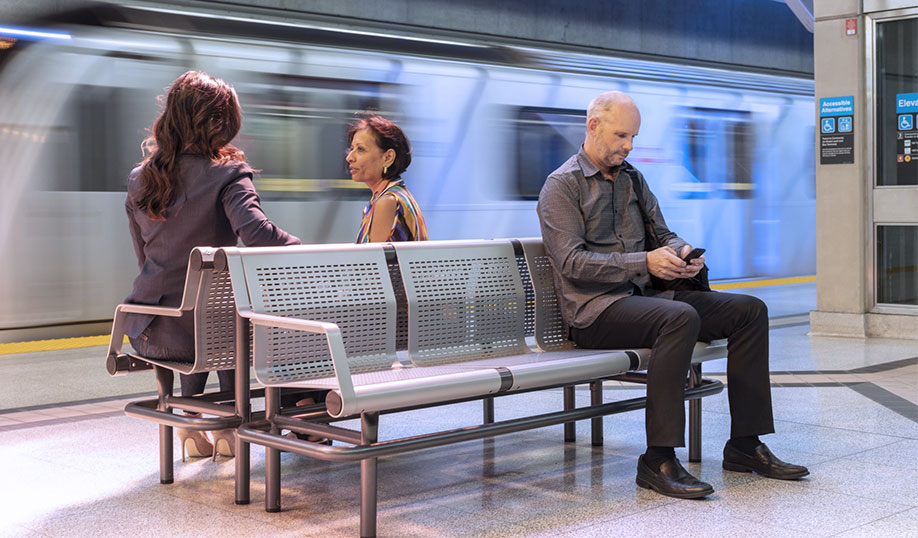 people sitting on a bench waiting as a subway arrives